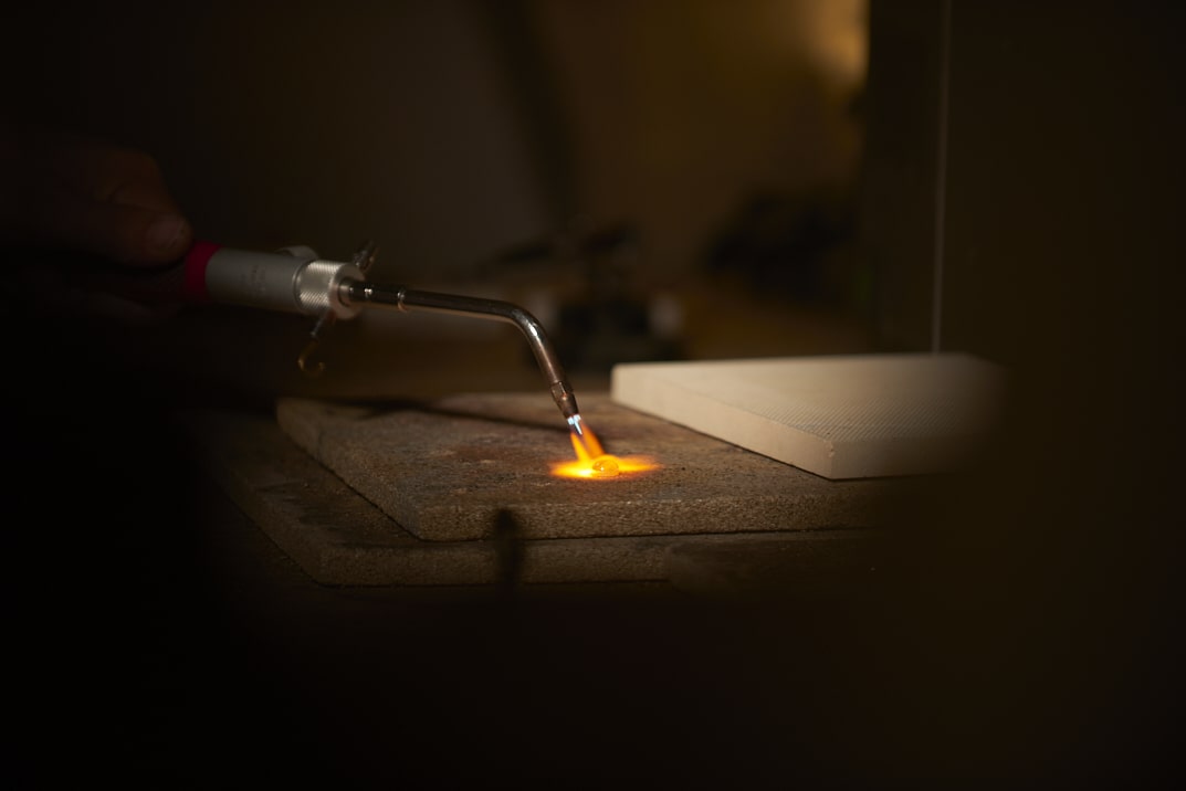 On voit les mains de la créatrice de bijoux Louise Vurpas en train de chauffer une pépite d'or. Bijouterie-joaillerie sur-mesure